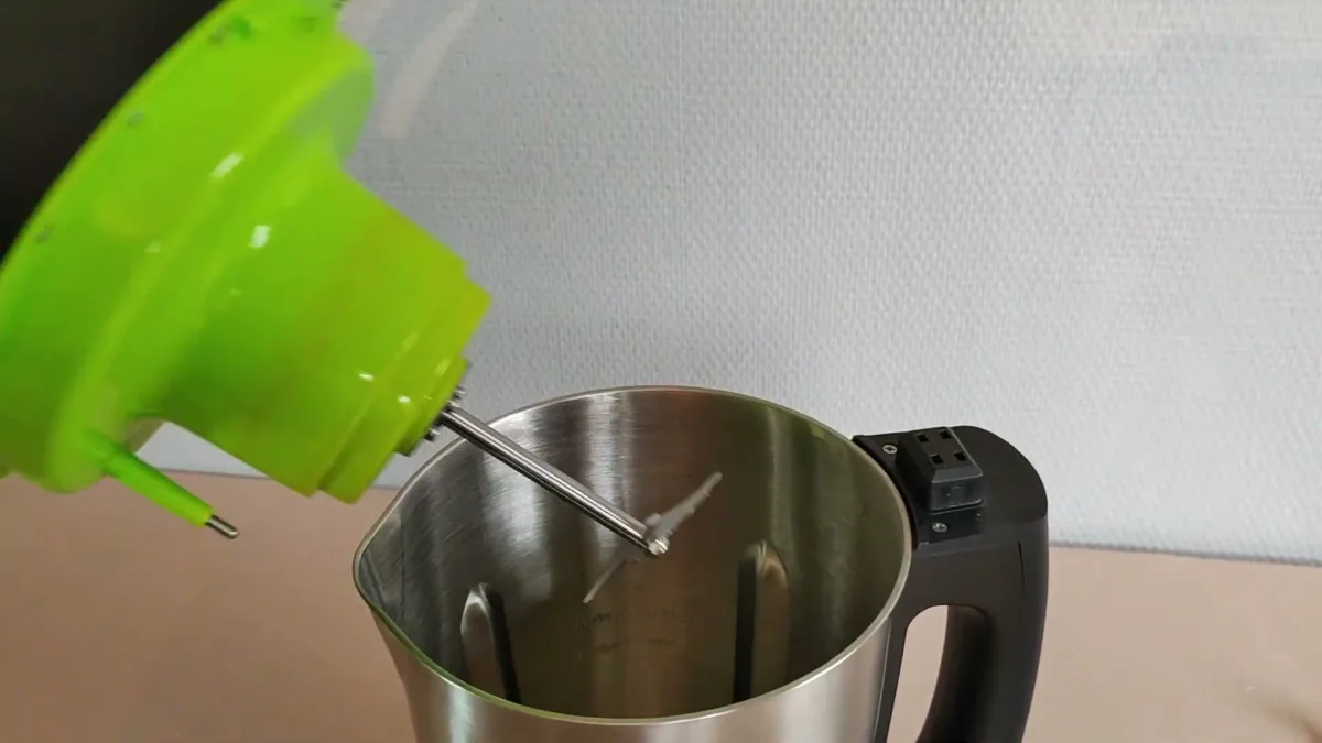 Couvercle du blender chauffant Domo DO498BL soulevé, avec la lame inox fixée dessous, au-dessus du bol inox