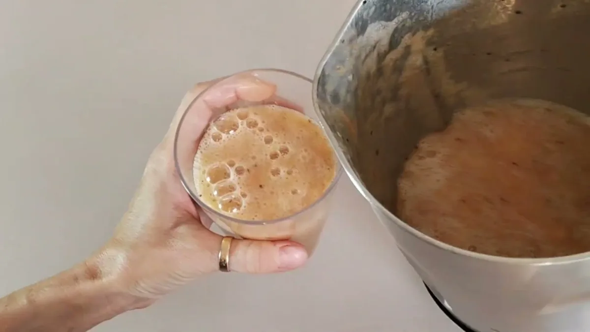 Smoothie aux fruits versé dans un verre depuis le bol du blender chauffant Domo DO498BL