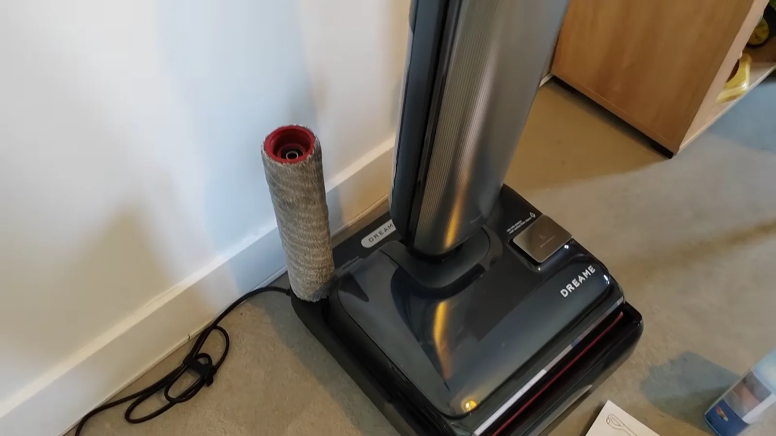 Le Dreame T16 Pro Heat posé sur sa base de charge, avec le rouleau de rechange rangé à côté