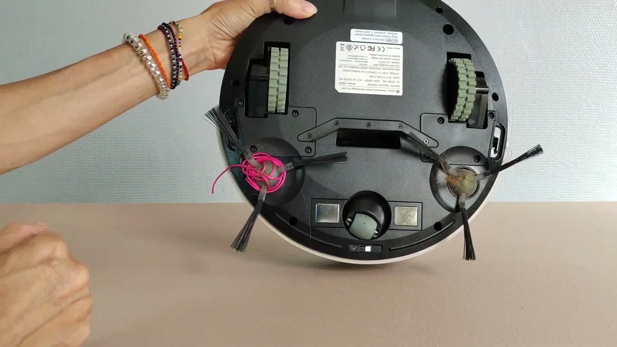 Dessous du Lefant M210P : un fil et des cheveux entortillés autour des brosses latérales