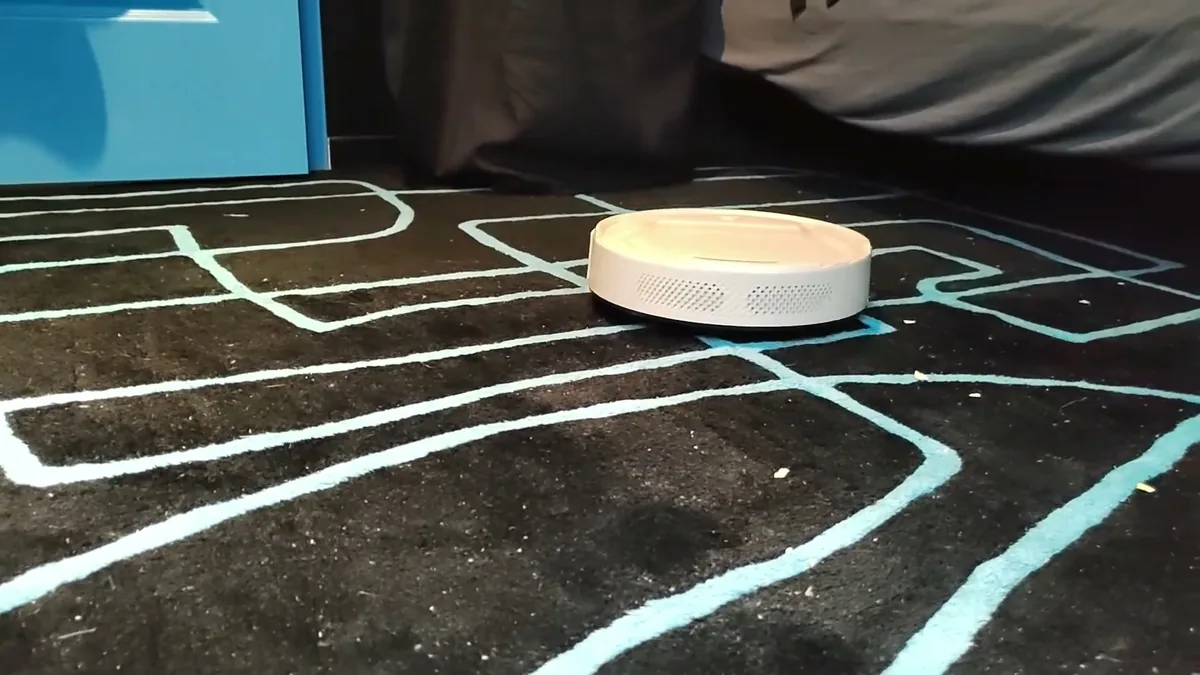 Le Lefant M210P sur un tapis en laine noir à motifs bleus, des miettes restent prises dans les fibres